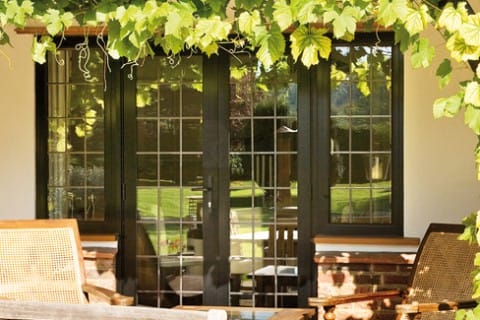 Exterior View of Patio Doors with Greenery and Chairs